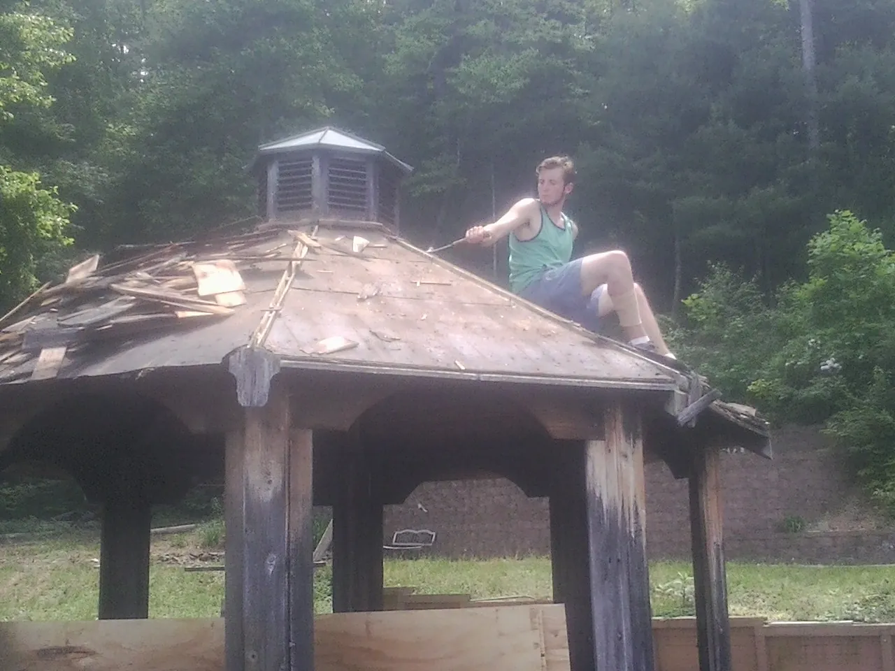 Tearing the old roof off a wooden gazebo before new shakes in King