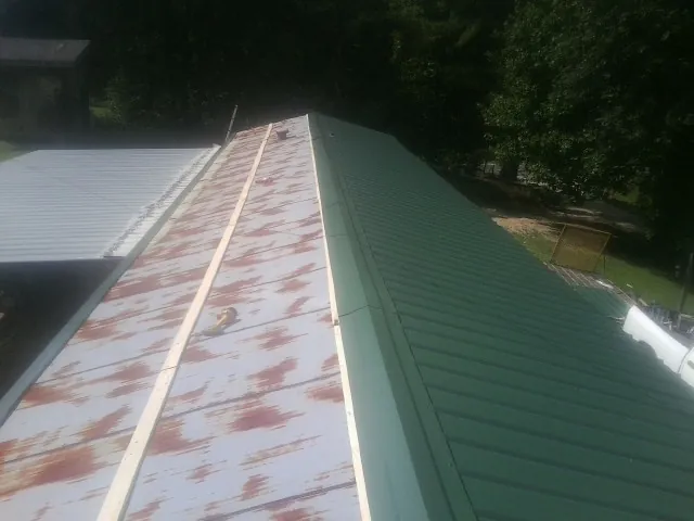 Old rusted panels beside newly installed green metal roofing — Wind Damage Roof Repair by Roofing Brothers in King