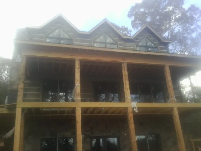 Dormers and porch framing on a large log home under construction — Roof Coating work by our crew in King