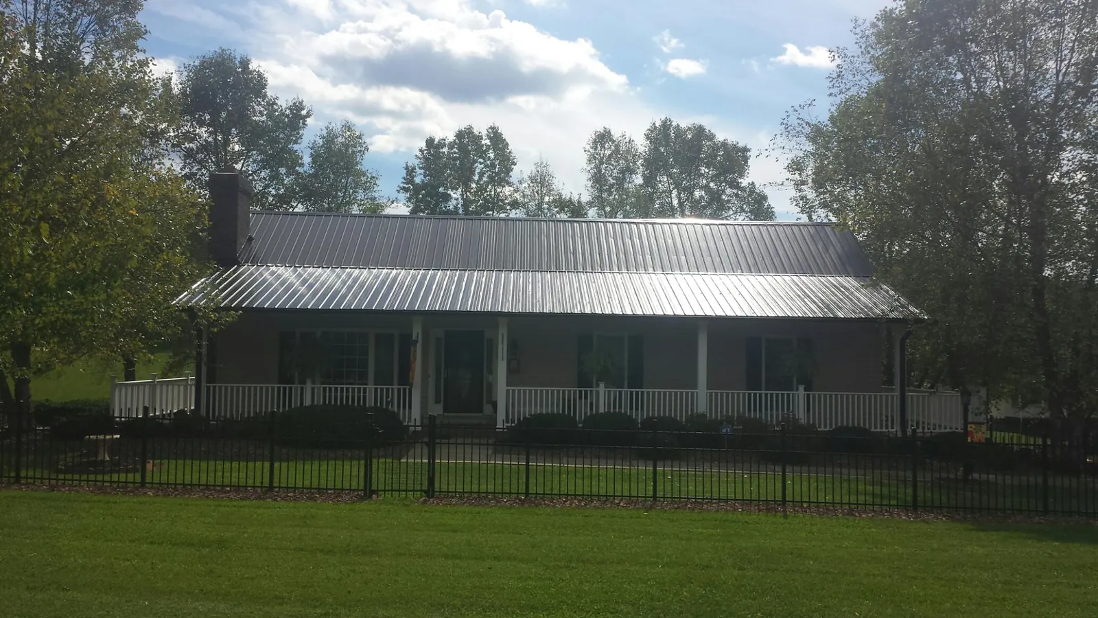Gray metal roof on a brick ranch with a full width front porch — Gutter Guard Installation work by our crew in King